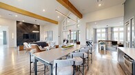 This elegantly designed single-floor clubhouse offers a sophisticated and welcoming environment with an open-concept layout that flows seamlessly across multiple functional areas. Soaring vaulted ceilings with exposed wooden beams lend a dramatic sense of height and warmth, while abundant natural light pours in through expansive windows and clerestory glass panels, creating a bright and airy atmosphere throughout.

The reception area greets visitors with herringbone-patterned hardwood flooring, textured feature walls, and richly upholstered rust-toned lounge chairs arranged beneath bold abstract artwork. A staffed desk with modern furnishings provides a professional yet approachable welcome point.

The central gathering space features a large communal dining table with upholstered bar seating beneath sleek pendant lighting and natural wood beams, flanked by multiple lounge zones with contemporary sofas and accent chairs. A dramatic chevron-patterned dark wood accent wall frames a recessed flat-screen display, while a separate lounge area showcases a striking marble tile feature wall with another media display and leather seating.

A dedicated game room includes a shuffleboard table and casual seating beneath curated artwork. The kitchen and bar area features teal accent walls, pendant lighting, open shelving, and a generous island with bar stools. Throughout, light hardwood flooring, curated art, and designer furnishings create a cohesive, upscale ambiance.