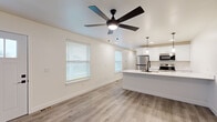 Located at 6806 E County Line Rd in Indianapolis, Indiana, this thoughtfully updated 2-bedroom, 1-bathroom single-story home offers a clean, modern aesthetic throughout. The open-concept living area and kitchen are unified by light-toned luxury vinyl plank flooring and neutral walls, creating a bright, welcoming atmosphere. Multiple windows fitted with white blinds fill the space with natural light, complemented by a stylish ceiling fan with integrated lighting. The front entry features a classic paneled white door, adding a touch of character to the space. The kitchen is a standout, boasting crisp white shaker cabinetry, striking marble-look quartz countertops, a stainless steel appliance suite, and a large island with a matte black undermount sink and pendant lighting above — ideal for both cooking and entertaining. The full bathroom is finished with the same attention to detail, featuring a white vanity with quartz countertop, matte black fixtures, and a soaking tub with tiled surround. Both bedrooms are well-proportioned and bright, each equipped with ceiling fans. The primary bedroom offers generous closet space with sliding paneled doors and a large window overlooking the exterior. The second bedroom provides direct sightlines to the front entry, adding connectivity to the layout.