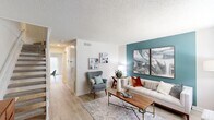 Located in Huntsville, Alabama, this two-story, two-bedroom, two-bathroom home offers a well-organized layout spread across two floors. The main level features an open living and dining area bathed in natural light from large windows and a glass door that leads to the exterior. The living room showcases light wood-style flooring, a textured ceiling, and a striking teal accent wall that adds a vibrant focal point to the space. The kitchen is fully equipped with white shaker-style cabinetry, granite countertops, stainless steel appliances including a range, microwave, dishwasher, and refrigerator, and a single-basin sink — combining both style and function. Upstairs, both bedrooms feature plush carpet flooring and ceiling fans. The spacious primary bedroom includes dual closets and a calming teal accent wall, while the second bedroom is similarly well-appointed with ample closet space and a ceiling fan. Each of the two bathrooms features a granite-topped vanity with a white undermount sink, white subway tile wainscoting, and a shower/tub combination. A hallway connects the upper-level rooms, and a staircase links both floors. The overall aesthetic is clean, modern, and cohesive throughout.