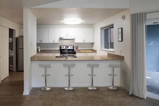 Renovated Package I kitchen with stainless steel appliances, white cabinetry, and grey quartz countertops - eaves Redmond Campus