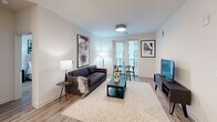 Located at 222 N West St in the heart of downtown Raleigh, NC, this thoughtfully designed 2-bedroom, 2-bathroom residence offers a clean, contemporary aesthetic throughout. The open-concept living area seamlessly connects the kitchen, dining, and living spaces, all finished with warm wood-look flooring and crisp white walls. The modern kitchen is a standout feature, boasting a large center island with quartz countertops, white cabinetry, stainless steel appliances, and globe pendant lighting that adds a stylish focal point. The living and dining area is bathed in natural light from full-length windows and a glass door leading to a private balcony. Both bedrooms are well-appointed, featuring ceiling fans, large windows, and generous closet space. The primary suite includes a spacious walk-in closet with custom built-in shelving and drawers. The en-suite bathroom offers a dual-sink vanity with a backlit mirror and a glass-enclosed tile shower. The second bathroom mirrors the same refined finishes. Additional highlights include multiple closets, a dedicated laundry area, and a utility room, ensuring ample storage throughout. The overall ambiance is light, airy, and move-in ready.