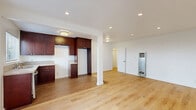 Located in the heart of Los Angeles on N Hayworth Ave, this single-floor, one-bedroom, one-bathroom residence offers a well-organized layout across a comfortable footprint. Light wood flooring runs throughout the main living areas, creating a warm and cohesive aesthetic.

The open-plan living and dining area is bright and airy, featuring recessed lighting, white walls, and a large front-facing window with vertical blinds that frame greenery views and invite natural light. A wall-mounted heater unit is integrated into the living space.

The kitchen flows naturally from the living area and is appointed with rich dark mahogany cabinetry, granite countertops, a stainless steel dishwasher, and a dedicated space for a refrigerator. Tile flooring distinguishes the kitchen zone, while a structural column marks the transition to the living space.

The bedroom is a well-proportioned, quiet retreat featuring light wood floors, a window with natural light, and a mirrored sliding closet. The unit includes a total of four closets, providing generous storage throughout. A hallway connects the main spaces efficiently.

The bathroom is a standout feature, showcasing a full tub and shower combination enclosed by a sleek glass sliding door and finished with elegant marble-style tile surround, complemented by a built-in niche and a frosted window above.