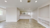 Located at 7359 Kester Ave in the Van Nuys neighborhood of Los Angeles, this three-bedroom, three-bathroom tri-level home offers a thoughtfully designed layout spread across three floors. The ground level houses an attached garage equipped with an electric vehicle charging station and an automatic opener, providing both convenience and modern utility.

The main living floor features a bright, open-concept living and dining area with light wood-look tile flooring, recessed lighting, and a sleek built-in fireplace. Large windows invite natural light and offer views of surrounding greenery. The kitchen is well-appointed with white shaker cabinetry, stone countertops, a subway tile backsplash, stainless steel gas range, dishwasher, and a peninsula that opens to the living space — ideal for entertaining. A dedicated laundry room with overhead cabinetry and a window rounds out this level.

The upper floor is home to three bedrooms, including a primary suite, each featuring light wood-look flooring and windows with neighborhood views. The three bathrooms are finished with clean, modern tile work, including a tub-shower combination with a glass sliding door and marble-style tile surround. Multiple closets and hallways provide ample storage throughout. The home's neutral palette and consistent finishes create a cohesive, move-in-ready atmosphere.