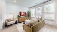 Located at 289 W Laughlin Ln in Celina, TX, this thoughtfully designed one-bedroom, one-bathroom residence offers a smart, efficient layout across a single floor. The bright living room is anchored by large windows dressed with sheer curtains and wood-slat blinds, flooding the space with natural light. Light-toned hardwood-style flooring runs throughout the main living areas, lending a clean, contemporary feel.

The galley-style kitchen is a standout feature, showcasing white shaker cabinetry, stainless steel appliances — including a French door refrigerator, range, microwave, and dishwasher — and sleek white countertops. A kitchen island with an undermount sink provides additional prep space and a casual gathering spot. Pendant lighting adds a polished finishing touch.

The bedroom is a comfortable retreat finished with plush carpet, a ceiling fan, and large windows that invite natural light while offering outdoor views. A dedicated closet provides practical storage.

The bathroom is cleanly appointed with a white quartz vanity, matte black fixtures, wood-look tile flooring, and a full tub-shower combination with large-format tile surround. A hallway connects all rooms, keeping the layout organized and easy to navigate. The overall design is modern, cohesive, and move-in ready.