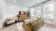 Located at 289 W Laughlin Ln in Celina, TX, this thoughtfully designed one-bedroom, one-bathroom residence offers a smart, efficient layout across a single floor. The bright living room is anchored by large windows dressed with sheer curtains and wood-slat blinds, flooding the space with natural light. Light-toned hardwood-style flooring runs throughout the main living areas, lending a clean, contemporary feel.

The galley-style kitchen is a standout feature, showcasing white shaker cabinetry, stainless steel appliances — including a French door refrigerator, range, microwave, and dishwasher — and sleek white countertops. A kitchen island with an undermount sink provides additional prep space and a casual gathering spot. Pendant lighting adds a polished finishing touch.

The bedroom is a comfortable retreat finished with plush carpet, a ceiling fan, and large windows that invite natural light while offering outdoor views. A dedicated closet provides practical storage.

The bathroom is cleanly appointed with a white quartz vanity, matte black fixtures, wood-look tile flooring, and a full tub-shower combination with large-format tile surround. A hallway connects all rooms, keeping the layout organized and easy to navigate. The overall design is modern, cohesive, and move-in ready.
