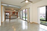 This single-floor unit showcases a distinctive industrial-modern design characterized by polished concrete floors that run continuously throughout the space, creating a cohesive and low-maintenance foundation. Exposed metallic ductwork runs along the ceilings, lending an authentic loft aesthetic that is both functional and visually striking.

The kitchen is a standout feature, outfitted with warm-toned cherry wood cabinetry, stainless steel appliances including a French door refrigerator, electric range with hood vent, dishwasher, and microwave. A stainless steel island with a butcher block counter extension offers additional prep space and casual seating. Large sliding glass doors adjacent to the kitchen flood the area with natural light and provide direct outdoor access with views of surrounding greenery.

The living and sleeping areas are generously proportioned open rooms with neutral walls, wood baseboards, and ceiling fans for comfort. Barn-style sliding doors add a modern-industrial touch to interior transitions. Exposed ductwork continues through these rooms, reinforcing the loft character.

The bathroom is cleanly appointed with a full tub-shower combination, a wood-framed vanity with an integrated sink, a large mirror, and coordinating storage cabinetry. The consistent use of concrete flooring and warm wood tones throughout ties the entire space together cohesively.