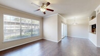 Located at 801 Legacy Dr in Plano, TX, this one-bedroom, one-bathroom residence offers a well-organized layout across a single floor. The combined kitchen and living area forms the heart of the home, featuring rich dark hardwood-style flooring, crown molding, and a ceiling fan that enhances airflow and comfort. Built-in open shelving adds both character and functional storage to the living space, while a pendant light fixture anchors the dining area. A sliding glass door brings in natural light and connects the living area to the outdoors. The kitchen is a standout, outfitted with bold dark cabinetry, granite-style countertops, a mosaic tile backsplash, and black appliances including a range, microwave, and dishwasher. A pass-through counter opens the kitchen to the living area, creating an inviting, connected feel. The bedroom is carpeted for comfort and features a ceiling fan, a large window with natural light, and a mirrored sliding-door closet that adds depth and storage. Crown molding carries throughout the bedroom as well, maintaining a consistent design detail. The bathroom is clean and functional, featuring a full tub-shower combo with white tile surround. A hallway and dedicated closet complete the layout, providing practical everyday storage.