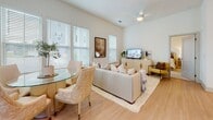 Located at 1000 Artistry Dr in Midlothian, Virginia, this single-floor residence offers a thoughtfully designed layout filled with natural light throughout. The open-concept kitchen is a standout feature, showcasing crisp white cabinetry extending to the ceiling, a large quartz waterfall island with bar seating, stainless steel appliances including a built-in microwave, range, and french door refrigerator, and a textured tile backsplash — all set atop light hardwood flooring.

The living and dining areas are bright and airy, benefiting from multiple large windows with views of the surrounding greenery. The living room features a ceiling fan, light hardwood floors, and generous space for both lounging and dining. A glass-paneled exterior door provides direct outdoor access, enhancing the open feel of the space.

The bedrooms are carpeted and serene, each with large windows that invite natural light and views of the outdoors. The primary bedroom is complemented by an en-suite bathroom featuring tile flooring, a glass-enclosed shower, a dual-sink vanity with white cabinetry, and a large mirror. A spacious walk-in closet with wire shelving and ample hanging space provides excellent storage. The neutral color palette throughout the residence creates a cohesive and calming ambiance.