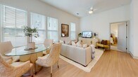 Located at 1000 Artistry Dr in Midlothian, Virginia, this single-floor residence offers a thoughtfully designed layout filled with natural light throughout. The open-concept kitchen is a standout feature, showcasing crisp white cabinetry extending to the ceiling, a large quartz waterfall island with bar seating, stainless steel appliances including a built-in microwave, range, and french door refrigerator, and a textured tile backsplash — all set atop light hardwood flooring.

The living and dining areas are bright and airy, benefiting from multiple large windows with views of the surrounding greenery. The living room features a ceiling fan, light hardwood floors, and generous space for both lounging and dining. A glass-paneled exterior door provides direct outdoor access, enhancing the open feel of the space.

The bedrooms are carpeted and serene, each with large windows that invite natural light and views of the outdoors. The primary bedroom is complemented by an en-suite bathroom featuring tile flooring, a glass-enclosed shower, a dual-sink vanity with white cabinetry, and a large mirror. A spacious walk-in closet with wire shelving and ample hanging space provides excellent storage. The neutral color palette throughout the residence creates a cohesive and calming ambiance.