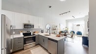 Located at 723 Wheatland St in Phoenixville, PA, this thoughtfully designed single-floor residence offers a seamless blend of modern style and practical living. The open-concept kitchen and living area serves as the heart of the home, featuring a two-tone cabinetry scheme with crisp white uppers and sage-gray lowers, stainless steel appliances, a peninsula with a waterfall-edge countertop and bar seating, and pendant lighting overhead. The kitchen flows effortlessly into a bright, airy living room filled with natural light from large windows dressed in sheer curtains and finished with wood-look flooring throughout. A separate den provides a flexible secondary space, ideal as a home office or reading room, with plush carpet and a distinctive textured accent wall. The primary bedroom features a bold accent wall, plush carpet, natural light from a generous window, and direct access to both a walk-in closet and the full bathroom. The bathroom is finished with a floating vanity, wood-look tile flooring, and a glass-enclosed tub and shower. Additional highlights include three closets for ample storage and a dedicated laundry area, rounding out this well-appointed Phoenixville residence.