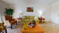 This single-floor residence offers a well-organized layout designed for comfortable everyday living. The living room serves as the central gathering space, featuring neutral-toned wall-to-wall carpeting, a textured ceiling, and a large sliding glass door fitted with vertical blinds that allows natural light to flow in while providing access to an outdoor area. The room accommodates both a seating arrangement and an entertainment area with ease.

Adjacent to the living room, the dining area provides a defined space for meals, with a window offering additional natural light. The galley-style kitchen runs parallel along one side of the unit, featuring warm wood cabinetry lining both walls, laminate countertops, hardwood-style flooring, and a full suite of appliances including a range and refrigerator. A pass-through view connects the kitchen directly to the dining space.

The bedroom is generously proportioned, with soft carpeting, a large closet, and a window that brings in natural light. The full bathroom includes a wide vanity with a single sink, ample under-sink cabinetry, a large mirror, and a shower-tub combination, all finished with hardwood-style flooring for a clean, cohesive look throughout.