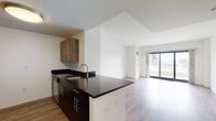 Located at 66 Summer St in downtown Stamford, Connecticut, this contemporary single-floor residence offers a thoughtfully designed open-concept layout. The living and dining area is anchored by warm wood-look flooring, track lighting, and expansive floor-to-ceiling sliding glass doors that open to a private outdoor terrace, framing striking views of the Stamford skyline. Natural light flows generously throughout the main living space, creating a bright and airy atmosphere.

The kitchen is seamlessly integrated into the living area via a peninsula island featuring dark granite countertops, dark cabinetry, and a stainless steel sink. The full kitchen is equipped with stainless steel appliances, including a refrigerator and range, complemented by a mix of dark and natural wood-toned upper cabinetry.

The bedrooms are finished with plush carpeting and clean white walls, offering a comfortable and quiet retreat. The primary bedroom includes a large closet and its own access to the outdoor terrace with panoramic city views. The bathroom is well-appointed with large-format floor tiles, a full soaking tub and shower surrounded by classic white subway tile, and a floating wood-toned vanity with ample storage.