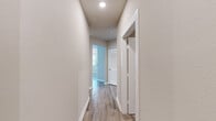 Located at 198 Mill Bayou Blvd in Lynn Haven, Florida, this two-story home offers a thoughtfully organized layout spread across two floors. The ground level houses a garage with a automatic opener, providing generous vehicle and storage space with a clean concrete floor.

The main living level features light-toned luxury vinyl plank flooring throughout the common areas, complemented by neutral wall tones that create a bright, cohesive aesthetic. The entry opens to a spacious living area with vaulted ceilings, multiple windows with blinds, and an elegant chandelier. A glass-paneled front door with transom window allows natural light to flow into the foyer. The kitchen includes white cabinetry, stainless steel appliances, and a window overlooking the exterior.

Both bedrooms are carpeted and equipped with ceiling fans. The primary bedroom connects directly to its en-suite bathroom, which features white cabinetry, a quartz countertop, and dual sinks with brushed nickel fixtures. A dedicated closet offers wire shelving for organized storage. The second bedroom includes its own walk-in closet with wire shelving. A dedicated laundry room with wire shelving overhead and washer/dryer hookups completes the upper level. Hallways are finished with hardwood-style flooring and recessed lighting.