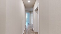 Located at 198 Mill Bayou Blvd in Lynn Haven, Florida, this two-story home offers a thoughtfully organized layout spread across two floors. The ground level houses a garage with a automatic opener, providing generous vehicle and storage space with a clean concrete floor.

The main living level features light-toned luxury vinyl plank flooring throughout the common areas, complemented by neutral wall tones that create a bright, cohesive aesthetic. The entry opens to a spacious living area with vaulted ceilings, multiple windows with blinds, and an elegant chandelier. A glass-paneled front door with transom window allows natural light to flow into the foyer. The kitchen includes white cabinetry, stainless steel appliances, and a window overlooking the exterior.

Both bedrooms are carpeted and equipped with ceiling fans. The primary bedroom connects directly to its en-suite bathroom, which features white cabinetry, a quartz countertop, and dual sinks with brushed nickel fixtures. A dedicated closet offers wire shelving for organized storage. The second bedroom includes its own walk-in closet with wire shelving. A dedicated laundry room with wire shelving overhead and washer/dryer hookups completes the upper level. Hallways are finished with hardwood-style flooring and recessed lighting.