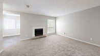 Located at 3600 Park Lake Ln in Peachtree Corners, GA, this single-story, 2-bedroom, 2-bathroom home offers a well-organized and functional layout. The entrance opens into a spacious combined living and dining area highlighted by vaulted ceilings, neutral carpet, and a charming stone-hearth fireplace with a classic white mantle. Natural light flows in through large windows dressed with blinds, enhancing the open, airy feel of the main living space. The galley-style kitchen is thoughtfully updated with white shaker cabinetry, granite countertops, a stainless steel sink with brushed gold fixtures, and stainless steel appliances including a refrigerator and dishwasher, all set on wood-look tile flooring. A dedicated den provides additional flexible living space. Both bedrooms are carpeted and feature neutral walls and ample natural light, with the primary bedroom offering a generous footprint. The two bathrooms are finished with granite vanity tops, undermount sinks, and brushed nickel fixtures, with one bath including a full tub/shower combo. A dedicated laundry room with shelving and in-unit washer hookups adds everyday convenience. Five closets throughout provide abundant storage.