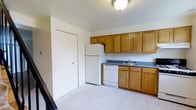 This two-story townhome at Bright Meadows Townhomes offers a straightforward and functional layout designed for comfortable everyday living. The kitchen is well-equipped with warm honey-toned wood cabinetry that provides generous storage across both upper and lower cabinets. A full suite of white appliances — including a refrigerator, dishwasher, and additional cooking appliances — is included, along with a double-basin sink set into a dark countertop. The light-toned tile flooring in the kitchen is easy to maintain and gives the space a clean, bright feel. A closet adjacent to the kitchen provides convenient additional storage. The white walls and ceiling throughout keep the interior feeling open and airy. Spread across two floors, the home provides a natural separation between living and sleeping areas, a layout well-suited for both individuals and families. The overall design is practical and low-maintenance, making it an ideal residence for those seeking a comfortable, move-in-ready townhome environment at Bright Meadows.