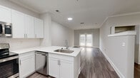 Located at 2430 Cheshire Bridge Rd NE in Atlanta's vibrant Cheshire Bridge neighborhood, this one-bedroom, one-bathroom unit is thoughtfully designed to maximize every square foot of its compact footprint. Hardwood-style flooring runs throughout, complemented by crisp white walls, crown molding, and bold white baseboards that lend a clean, cohesive aesthetic.

The open-concept kitchen is a standout feature, outfitted with white shaker cabinetry, white quartz countertops, a subway tile backsplash, and a full suite of stainless steel appliances including a refrigerator, electric range, over-the-range microwave, and dishwasher. A peninsula with an undermount sink connects seamlessly to the living area, which benefits from natural light streaming through double French doors.

The generously sized primary bedroom accommodates a variety of furniture arrangements and features crown molding and a ceiling fan. A dedicated closet provides practical storage. The bathroom is finished with a white shaker vanity, quartz countertop, and a full tub-shower combination with tiled surround and a curved shower rod. Neutral gray tones and consistent finishes tie the space together for a modern, move-in-ready feel.