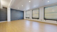 Located on the sixth floor at 424 South Broadway in the heart of downtown Los Angeles, this 2-bedroom, 1-bathroom unit offers a clean, modern aesthetic across a single well-organized floor. Light wood flooring flows throughout, creating a warm, cohesive foundation in every room. The open living area is defined by a striking exposed brick accent wall painted in a cool grey tone, complemented by large black-framed windows with zebra blinds that allow for adjustable natural light. Recessed ceiling lighting adds a polished finish to the space. The kitchen features sleek two-tone cabinetry in light and dark grey, stainless steel appliances including a range, microwave, and refrigerator, a white subway tile backsplash, and light countertops — a fully functional and stylish cooking space. Both bedrooms are bright and well-proportioned, with the primary bedroom offering a mirrored closet and a window with zebra blinds. The bathroom presents a contemporary design with dark tile surround, a frosted glass partition separating the shower area, black hardware accents, and a wall-mounted sink, delivering a refined and functional layout throughout.
