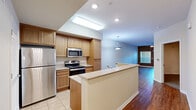 Located at 300 Crescent Dr in Vacaville, CA, this well-appointed one-bedroom, one-bathroom residence offers a thoughtfully designed single-floor layout with generous living space throughout. The open-concept living and dining area is finished with warm hardwood-style flooring and features large windows and a ceiling fan, creating a bright and comfortable environment. Sliding glass doors lead directly to a private balcony, allowing natural light to pour in and providing a seamless indoor-outdoor connection. The kitchen is equipped with warm wood cabinetry, granite-style countertops, a peninsula with a sink, stainless steel appliances including a refrigerator, range, and microwave, and recessed lighting — making it both functional and visually appealing. The bedroom is a well-sized retreat with plush carpeting, an accent wall in a rich earth tone, and direct access to a closet and the full bathroom. The bathroom features tile flooring, a single vanity with wood cabinetry, and a full soaking tub with shower. A dedicated in-unit laundry area with wire shelving adds everyday convenience. The residence combines neutral tones with warm finishes throughout, offering a comfortable and practical living environment.