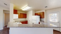 This single-story, 2-bedroom, 2-bathroom home offers a practical and comfortable layout across a well-utilized floor plan. The kitchen is a standout feature, equipped with warm wood cabinetry, granite-style countertops, a built-in breakfast bar, white appliances including a range and refrigerator, and bright overhead fluorescent lighting. A window near the kitchen entry offers views of the surrounding greenery, adding a sense of connection to the outdoors.

The living areas are bright and open, with neutral-toned walls and rich hardwood-style flooring that flows consistently throughout the home. Each bedroom is generously proportioned, featuring ceiling fans, natural light from multiple windows with blinds, and access to closet space. The primary bedroom is notably spacious and includes a dedicated closet.

Both bathrooms are clean and functional. One features a pedestal sink, toilet, and hardwood-style flooring, while the second includes a shower-tub combination with a glass sliding door. Chrome hardware and towel bars add a polished finish to both spaces.

Hallways and closets provide practical storage throughout. The home's consistent use of hardwood-style flooring, neutral paint palette, and well-placed windows creates a cohesive, airy ambiance suited for comfortable everyday living.