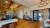 Located at 4000 S Dixieland Rd in Rogers, Arkansas, this single-story community clubhouse offers a thoughtfully designed amenity space that blends function and style. Warm hardwood floors flow throughout the main areas, complemented by neutral tones, crown molding, and exposed wood beam accents that lend a welcoming, upscale character.

The main lounge area serves as the heart of the space, featuring a striking reclaimed wood accent wall with a mounted television, comfortable seating, and an open layout that connects seamlessly to a dining area. Large windows frame views of the outdoor pool, flooding the dining room with natural light. A French door provides direct access to the pool deck, making this area ideal for community gatherings.

The fully equipped kitchenette is outfitted with white shaker cabinetry, dark countertops, floating wood shelves, and a bold mosaic tile backsplash, providing ample prep and serving space.

The fitness center is well-appointed with rubber flooring, ceiling fans, and an extensive array of equipment including treadmills, ellipticals, a cable machine, rowing machine, spin bikes, free weights, and stability balls. An adjacent room with a ProSun stand-up tanning booth adds a wellness-focused amenity. A glass-paneled door leads to private office spaces, rounding out this versatile and comprehensive community facility.