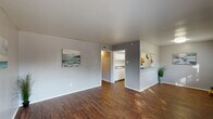 This single-story, two-bedroom, one-bathroom unit in Houston, TX is designed with a practical and cohesive layout. Rich, dark hardwood-style flooring runs continuously throughout the entire space, providing a warm and unified aesthetic against the cool gray-toned walls and bright white trim.

The living area is open and well-proportioned, receiving natural light through a front-facing window. A pass-through opening connects this space to the kitchen, enhancing the sense of openness between the two areas. The galley-style kitchen is efficiently arranged with white cabinetry lining both sides, granite-look countertops, a white gas range, refrigerator, and a double-basin sink. Ample upper and lower cabinet storage makes this kitchen highly functional.

A hallway connects the living area to the two bedrooms and bathroom. Both bedrooms feature ceiling fans with light fixtures, and one bedroom includes a walk-in closet. The full bathroom is appointed with a white vanity offering under-sink storage, a tub-shower combination, and consistent hardwood-style flooring. The overall ambiance of the unit is clean, neutral, and move-in ready.