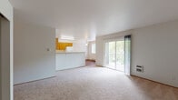 This single-floor unit offers a practical and functional layout with a clean, neutral aesthetic throughout. The living area is generously sized, featuring wall-to-wall carpet and a large sliding glass door that opens to a private balcony, flooding the space with natural light and providing views of surrounding greenery. A half-wall partition seamlessly connects the living area to the kitchen, which is equipped with warm honey-toned wood cabinetry, white appliances including a refrigerator, range, and dishwasher, and durable wood-look flooring. A pendant light and fluorescent fixture illuminate the kitchen workspace.

The two bedrooms are carpeted and well-proportioned, each featuring a window with blinds that bring in natural light, and baseboard heating units for year-round comfort. One bedroom includes access to a walk-in closet with built-in shelving, offering ample storage. The unit includes two bathrooms: one features a wood-toned vanity with a large mirror and wood-look flooring, while the other contains a full tub-shower combination, toilet, and vanity. The overall ambiance is bright, clean, and move-in ready.