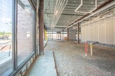 Located at 215 Monticello Ave in Williamsburg, Virginia, this single-story commercial shell space is currently in active construction, presenting a blank canvas ready for a custom tenant build-out. The structure features a robust steel beam and column framework supporting an exposed metal deck ceiling, through which an extensive network of roughed-in mechanical, plumbing, and electrical conduit runs are already in place — providing a strong infrastructure foundation for future improvements.

The open floor plan is expansive, with gravel-covered ground throughout indicating pre-slab preparation. Drywall partitions are partially erected, beginning to define distinct zones within the interior. Concrete masonry unit walls anchor structural core areas, while foil-faced insulation is visible along portions of the perimeter, underscoring the building envelope's energy efficiency design.

A standout feature is the generous storefront glazing system along multiple exterior walls, comprised of large floor-to-ceiling aluminum-framed windows and glass entry doors. These bring in abundant natural light and offer prominent visibility to the surrounding streetscape and adjacent commercial corridor — a significant asset for any retail, restaurant, or service-oriented tenant. The building's position along Monticello Ave places it in close proximity to Williamsburg's active commercial district, offering strong foot and vehicle traffic exposure.