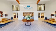 Located at 650 George Washington Way in Richland, Washington, this amenity center at Park Place Apartments spans a single, generously proportioned floor designed to serve as a hub for residents and visitors alike. The grand entrance lobby sets an impressive tone with soaring ceilings, warm wood beam accents, large-format light tile flooring, and floor-to-ceiling glass doors that flood the space with natural light. A central round wooden table with fresh floral arrangements anchors the welcoming reception area, which features a built-in front desk and vibrant artwork on the walls. Adjacent to the lobby, an expansive lounge and co-working area offers a blend of casual seating, collaborative work tables, and oversized windows with views of the outdoors. This space is enhanced by high industrial-style pendant lighting and colorful, curated furnishings. A separate social lounge features garage-style glass doors that open to the exterior, seamlessly connecting indoor and outdoor living. The fully equipped fitness center provides high ceilings, abundant natural light, rubber flooring, cardio machines, a cable weight system, and mirrored walls. A dedicated conference room includes a substantial live-edge wood table, leather executive chairs, a mounted display screen, and a whiteboard. A clean, tile-floored hallway lined with artwork connects all areas, completing this well-appointed amenity space.