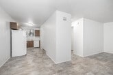 Located at 509 S 13th St in Boise, Idaho, this single-floor unit offers a straightforward and functional layout suited for comfortable everyday living. The open living and entry area is finished with light wood-style vinyl flooring that extends through the main spaces, giving the unit a clean and cohesive appearance. White walls throughout keep the interior bright and neutral.

The kitchen is equipped with warm wood-toned cabinetry providing ample upper and lower storage, light-colored countertops, a stainless steel sink positioned beneath a window that brings in natural light, and a white dishwasher. The efficient layout makes good use of available space.

The bedrooms feature wall-to-wall carpet, offering a softer, quieter environment. Each room is served by baseboard heating, ensuring consistent warmth throughout the colder months. One bedroom also includes a wall-mounted air conditioning unit for year-round climate control, along with a window fitted with blinds that allows for natural light and ventilation.

The unit's overall layout, as seen in the dollhouse view, includes distinct zones for living, sleeping, and kitchen use, connected by a central corridor. The interior presents a practical and livable space with essential amenities in a convenient Boise location.