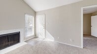 This single-floor space is designed with a clean, neutral aesthetic that creates a bright and cohesive atmosphere throughout. The main living area features wood-look plank flooring in a warm gray tone, complemented by soft beige walls and crisp white trim. A built-in cabinet with white shaker-style doors and a white countertop adds a functional accent to the living space. Multiple windows fitted with horizontal blinds allow generous natural light to fill the room, while a front entry door provides direct access to the exterior.

The kitchen is outfitted with white shaker cabinetry, light quartz-style countertops, and stainless steel appliances including a refrigerator and an electric range with an overhead ventilation hood, offering a practical and modern cooking environment.

The bedrooms are finished with plush carpet and feature neutral walls. At least one bedroom includes a walk-in closet with built-in shelving. A dedicated dining area benefits from a corner window arrangement that frames outdoor views and enhances the sense of openness.

The bathroom includes a white vanity with ample cabinet storage, a white countertop with an integrated sink, brushed nickel fixtures, a large mirror, and a tub-shower combination with tile surround, all set on wood-look tile flooring.