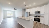 Located on Founder's Lane in Lebanon, Ohio, this single-story home offers four bedrooms, two bathrooms, and a well-designed layout that maximizes both function and comfort. The open-concept kitchen and living room form the heart of the home, where wood-look plank flooring flows seamlessly underfoot. The kitchen is appointed with white shaker cabinetry, granite-look countertops, a center island with an undermount sink, and stainless steel appliances including a refrigerator, range, and over-the-range microwave. The spacious living room features a ceiling fan, abundant natural light from large windows, and a doorway leading to the exterior. Bedrooms are carpeted for comfort, with the generously sized primary bedroom offering a walk-in closet equipped with wire shelving systems. Additional bedrooms are well-proportioned with built-in closets. The bathrooms are clean and functional, featuring a soaking tub with a tile surround. A dedicated laundry room with wood-look flooring and overhead wire shelving adds everyday convenience. The attached garage provides secure parking and extra storage space with an automatic door opener. Neutral tones and consistent finishes throughout create a cohesive, move-in-ready atmosphere.