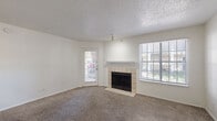 Located at 800 FM-1417 in Sherman, Texas, this one-bedroom, one-bathroom unit offers a functional and comfortable single-floor layout. The combined kitchen and living area forms the heart of the space, where a tile-surround wood-burning fireplace serves as a focal point in the living room. Natural light fills the room through a large window and a glass-paneled exterior door that opens to the outdoors. Textured ceilings and neutral carpet extend throughout the living areas, creating a cohesive and understated aesthetic. The kitchen features warm wood cabinetry, a double sink, white appliances including an electric range and refrigerator, and wood-look flooring that adds a practical, easy-to-clean surface. A hallway connects the main living area to the private bedroom, which is comfortably sized and includes a ceiling fan with light, a window with natural views, and plush carpet. Two closets provide ample storage throughout the unit. The bathroom is well-appointed with a full tub and shower combination, a vanity with wood cabinetry and a light countertop, and durable wood-look flooring. A hallway ties the layout together, ensuring smooth flow between all areas of the home.