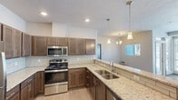 Located at 11797 E Broadway Ave in Spokane Valley, WA, this well-appointed one-bedroom, one-bathroom unit offers a practical and modern layout across a single floor. The open-concept kitchen and living area serves as the heart of the home, showcasing rich medium-toned cabinetry, granite countertops, a classic subway tile backsplash, and a full suite of stainless steel appliances including a range, over-the-range microwave, refrigerator, and double-basin sink. Pendant lighting above the kitchen peninsula adds a refined touch, while light wood-style flooring runs throughout the main living areas. The bedroom is a comfortable, carpeted retreat with a window providing natural light and a baseboard heating unit. The bathroom is clean and functional, featuring a full soaking tub and wood-style flooring. Three closets provide generous storage throughout the unit. A dedicated in-unit laundry space houses a full-size washer and dryer. The unit also includes a private patio, offering an outdoor extension of the living space. The overall design is modern and neutral, creating a move-in-ready environment with a clean, contemporary aesthetic throughout.