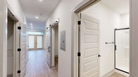 Located at 1130 Annondale Way in Fayetteville, NC, this single-floor, one-bedroom, one-bathroom unit offers a thoughtfully designed layout with contemporary finishes throughout. Light wood-look flooring flows seamlessly through every room, complemented by crisp white walls and clean-lined trim that create a bright, cohesive aesthetic.

The kitchen is a standout feature, showcasing a two-tone cabinet design — white upper cabinets paired with slate-blue lower cabinets — topped with granite countertops and a classic white subway tile backsplash. A full suite of stainless steel GE appliances, including a refrigerator, range, microwave, and dishwasher, along with an matte black faucet and open shelving, complete this well-equipped space.

A hallway with a sleek sliding barn door connects the living areas to the private spaces, adding a modern architectural touch. The living room is open and airy, lit by recessed lighting and framed by glass panel entry doors.

The bedroom is comfortably sized, featuring a ceiling fan, a window with blinds for natural light, and direct access to a dedicated closet with built-in rod storage. The bathroom is elegantly appointed with a granite-topped vanity, a large mirror, matte black hardware, and a frameless sliding glass walk-in shower enclosure.