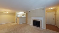 This single-floor unit is designed with a practical, open layout that connects the main living areas cohesively. The living room serves as the centerpiece, featuring a tiled-surround fireplace with a white wood mantle and crown molding that adds a refined architectural detail to the space. Neutral-toned carpet flows throughout, contributing to the warm, understated ambiance.

The kitchen is efficiently arranged in a galley configuration, featuring light wood cabinetry, laminate countertops, a stainless steel sink, and white appliances including a refrigerator, electric range, and built-in microwave. A peninsula with a breakfast bar visually connects the kitchen to the living area, enhancing the open-concept feel. The kitchen and bathrooms feature wood-look laminate flooring.

The bedrooms are carpeted and share a consistent neutral color palette. Each room includes a ceiling fan with light fixture and windows fitted with blinds, providing both ventilation and natural light. Closet access is provided in each bedroom.

Two full bathrooms each include a tub/shower combination, toilet, vanity with storage cabinetry, and a large mirror. A dedicated laundry room houses a full-size washer and dryer, with wire shelving above for added storage.
