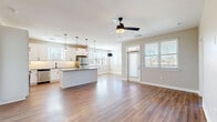 Located at 500 N Henry in Williamsburg, Virginia, this well-appointed 2-bedroom, 2-bathroom residence offers a thoughtfully designed single-floor layout. The open-concept kitchen and living area serves as the heart of the home, featuring warm hardwood-style flooring, abundant natural light from multiple windows with blinds, and a ceiling fan overhead. The kitchen is outfitted with white shaker cabinetry, a classic subway tile backsplash, granite countertops, stainless steel appliances, and a central island with pendant lighting — ideal for both cooking and entertaining. The spacious living area flows seamlessly toward a private entry door with additional window panels. Both bedrooms are carpeted for comfort, with the generously sized primary bedroom offering two windows, a ceiling fan, and access to a well-appointed bathroom featuring granite counters, white cabinetry, and a walk-in closet equipped with wire shelving. A dedicated laundry room includes a full-size washer and dryer with additional wire shelving above. Two closets, a hallway, and two full bathrooms complete this clean, modern floor plan designed for practical, comfortable living.
