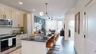 Located in Lawrenceville, GA, this thoughtfully designed 1-bedroom, 2-bathroom residence offers a well-appointed single-floor layout that maximizes every square foot. The open-concept kitchen and living area form the heart of the home, anchored by a striking island with dark granite countertops, a matte black faucet, and seating for casual dining. Light wood cabinetry extends to the ceiling, providing generous storage, while stainless steel appliances add a polished, contemporary finish. A sculptural pendant light hangs above the island, lending an artistic touch to the space. The kitchen flows seamlessly into the living room, where large windows invite abundant natural light and a bold slate-blue accent wall creates a warm, dynamic backdrop. Wood-look flooring runs throughout the main living areas, enhancing the cohesive aesthetic. The primary bedroom features plush carpet, a ceiling fan, and generous window coverage that fills the room with soft, natural light. Both bathrooms are finished with the same light wood cabinetry and dark granite countertops seen throughout the home, with clean white tile work in the bath. A dedicated laundry area with a stacked washer and dryer provides added everyday convenience, completing this well-rounded and modern residence.