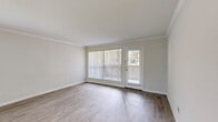 Located at 10225 Bissonnet St in Houston, TX, this 1-bedroom, 2-bathroom unit delivers a thoughtfully organized single-floor layout. The open living room is a bright, welcoming space featuring light wood-style luxury vinyl flooring, crown molding, and large windows fitted with blinds that allow ample natural light. A full-width sliding glass door leads to a private balcony, extending the living area outdoors with a view of surrounding greenery.

The galley-style kitchen is efficiently designed with warm wood cabinetry, granite-style countertops, tile backsplash, and black appliances including an electric range and refrigerator. It opens directly to the living area, creating a connected, functional flow.

The generously sized primary bedroom features plush carpet flooring, a ceiling fan with light fixture, a natural light window, and two closets — including a walk-in — providing ample storage. Both bathrooms are finished with wood vanities, granite-style countertops, and large mirrors with overhead lighting.

A hallway connects the rooms seamlessly, and additional storage is available throughout. The unit's neutral color palette and clean finishes create a bright, move-in ready atmosphere suited for comfortable Houston living.