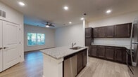 This single-floor residence offers a thoughtfully designed open-concept layout with a clean, modern aesthetic throughout. The kitchen serves as a central focal point, anchored by a large island with granite countertop and an integrated sink with stainless steel fixtures. Rich, dark espresso-toned cabinetry lines the walls, accented by a classic white subway tile backsplash and complemented by a full suite of stainless steel appliances, including a refrigerator, range, microwave, and dishwasher. Recessed lighting illuminates the kitchen and living areas, enhancing the open, airy feel of the connected space.

Light wood-style flooring flows consistently throughout the unit, providing a warm and cohesive foundation in every room. The living area benefits from natural light through a window with blinds and is equipped with a ceiling fan for added comfort.

The bedrooms are generously proportioned, each featuring the same wood-style flooring, neutral white walls, ceiling fans, and windows that bring in natural light. Closet access is present in at least one bedroom.

The bathroom maintains the same design language found throughout the unit, featuring a dark wood vanity with a granite countertop, a framed mirror, and light tile flooring, creating a polished, consistent finish.