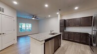 This single-floor residence offers a thoughtfully designed open-concept layout with a clean, modern aesthetic throughout. The kitchen serves as a central focal point, anchored by a large island with granite countertop and an integrated sink with stainless steel fixtures. Rich, dark espresso-toned cabinetry lines the walls, accented by a classic white subway tile backsplash and complemented by a full suite of stainless steel appliances, including a refrigerator, range, microwave, and dishwasher. Recessed lighting illuminates the kitchen and living areas, enhancing the open, airy feel of the connected space.

Light wood-style flooring flows consistently throughout the unit, providing a warm and cohesive foundation in every room. The living area benefits from natural light through a window with blinds and is equipped with a ceiling fan for added comfort.

The bedrooms are generously proportioned, each featuring the same wood-style flooring, neutral white walls, ceiling fans, and windows that bring in natural light. Closet access is present in at least one bedroom.

The bathroom maintains the same design language found throughout the unit, featuring a dark wood vanity with a granite countertop, a framed mirror, and light tile flooring, creating a polished, consistent finish.