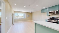 Located in Northridge, Los Angeles, this thoughtfully designed one-bedroom, one-bathroom unit offers a well-organized single-floor layout that maximizes every inch of its compact footprint. The open-concept main living area seamlessly integrates the living room, dining space, and kitchen, creating a connected and functional environment. Light wood-style flooring runs throughout the main area, complemented by warm beige walls and a textured ceiling with recessed lighting and a ceiling fan. A large sliding window floods the living space with natural light and frames views of the surrounding neighborhood and distant hills.

The kitchen is a standout feature, showcasing sage green shaker-style cabinetry paired with crisp white countertops and stainless steel appliances, including a gas range, microwave, and dishwasher. A peninsula provides additional counter space and a natural division between the kitchen and living area.

The bedroom offers a comfortable, carpeted retreat with its own window view, ceiling fan, and wall-mounted HVAC unit, along with access to two closets for ample storage. The full bathroom is clean and bright, featuring teal cabinetry with a white countertop, a full tub-shower combo, and light tile flooring consistent with the rest of the unit's cohesive design palette.