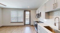 Located in Leander, TX, this efficient one-bedroom, one-bathroom unit offers a thoughtfully designed single-floor layout with modern finishes throughout. The entryway features light wood-style flooring and sliding barn-style doors, setting a contemporary tone from the moment you enter.

The kitchen is a standout feature, equipped with gray shaker-style cabinetry, light quartz countertops, a white subway tile backsplash, and a full suite of stainless steel appliances including a range, over-the-range microwave, dishwasher, and refrigerator. A deep stainless steel sink with a gooseneck faucet adds a refined touch, while a glass door and large window invite natural light and provide access to a private balcony.

The bedroom is a comfortable, carpeted retreat with a ceiling fan and ample room for furnishings. Its neutral palette and clean lines create a calm, restful environment.

The bathroom is well-appointed with gray shaker vanity cabinetry, a white quartz countertop, a framed mirror, overhead lighting, overhead storage cabinetry, and a full tub-shower combination with tile surround. Wood-look flooring ties the space together seamlessly.

Throughout the unit, recessed lighting, neutral wall tones, and consistent gray trim details create a cohesive, modern aesthetic well-suited for comfortable everyday living.