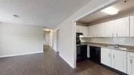 This single-floor residence offers a thoughtfully designed layout that balances functionality and comfort throughout. The open living area greets you upon entry, featuring rich dark hardwood-style flooring, neutral walls, and a ceiling fan overhead. A large window allows natural light to fill the space while offering views of greenery outside.

The kitchen is positioned just off the main living area and is equipped with ample white cabinetry, a classic subway tile backsplash, and a full suite of black appliances including a range, dishwasher, and refrigerator. A double-basin sink and generous counter space make this kitchen both practical and visually clean.

A hallway connects the living spaces to the bedrooms, each of which is carpeted for added warmth and comfort. The bedrooms are generously sized, featuring ceiling fans with light fixtures and windows with blinds that bring in natural light. The neutral tones throughout create a calm, versatile atmosphere.

The unit includes two bathrooms. One features a tub/shower combination with safety grab bars, a white vanity, and wood-look tile flooring. The second bathroom includes a bathtub, a white vanity with a mirror, and matching hardwood-style flooring. Together, the spaces offer a clean and functional home environment.