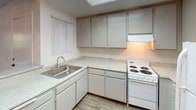 Located at 10829 Fulton Wells Ave in Santa Fe Springs, California, this single-floor unit offers a practical and well-organized layout designed for comfortable everyday living. The open-concept living and dining area features plush carpeting and flows seamlessly toward a sliding glass door that opens to a private balcony, allowing natural light to fill the space and providing outdoor views of the surrounding area. A textured ceiling adds a classic touch throughout the common areas.

The kitchen is efficiently designed in an L-shaped configuration, featuring ample gray cabinetry for storage, light-toned countertops, a stainless steel sink, and a coil-burner electric range. A skylight overhead brightens the workspace naturally, while wood-look flooring adds a clean, modern contrast to the cabinetry. A breakfast bar peninsula connects the kitchen to the living area, offering additional counter space and a casual dining option.

The bedroom is generously sized with soft carpeting, a ceiling fan with light fixture for climate control and illumination, and a walk-in closet providing substantial storage. The full bathroom is clean and functional, featuring a shower-tub combination, wood-look flooring, and a neutral color palette that gives the space a bright, fresh appearance. Overall, the unit presents a cohesive, move-in-ready environment with a straightforward and efficient design.