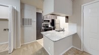 Located at 3009 Ira Young Dr in Temple, Texas, this single-floor residence offers a thoughtfully designed layout with contemporary finishes throughout. The kitchen serves as a functional centerpiece, featuring dark cabinetry, stainless steel appliances including a refrigerator, range, and microwave, as well as a granite-topped peninsula with an integrated sink. A classic subway tile backsplash adds a clean, modern touch to the cooking space.

The living area is carpeted and bathed in natural light through a large window and a glass door that provides direct access to the outdoors, creating a bright and welcoming atmosphere. Neutral-toned walls and a textured ceiling carry throughout the home, lending a cohesive and understated aesthetic.

The bedroom is generously proportioned with plush carpeting and is conveniently connected to a hallway that leads to a closet and the bathroom. The bathroom is well-appointed with large-format tile surrounding the bathtub and shower, a granite vanity countertop, dark cabinetry for storage, and an overhead cabinet for added organization. Tile flooring completes the polished look of the bathroom. Together, these features make this a comfortable and move-in ready home in Temple, TX.