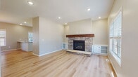 Located at 90–154 E Erie St in Oak Creek, Wisconsin, this two-story home offers a clean, modern aesthetic with quality finishes throughout. The main living area centers around a striking stone fireplace with a rich wood mantel and raised hearth, flanked by built-in white cabinetry for storage and display. Light hardwood flooring flows throughout the main level, complementing the neutral wall tones and recessed lighting that illuminate the open layout.

The kitchen is well-equipped with crisp white shaker-style cabinetry, quartz countertops, a classic subway tile backsplash, and a full suite of stainless steel appliances including a gas range, microwave, and refrigerator. A central island with a built-in sink adds both workspace and functionality.

Bedrooms are carpeted for comfort and feature neutral tones with windows that bring in natural light. A full bathroom includes a soaking tub with marble-style tile surround, hardwood-look flooring, and a dark-finished vanity with granite countertops. A half bath is also present. The dedicated laundry room offers ample storage with rich wood cabinetry above a utility sink, alongside side-by-side washer and dryer hookups. The home's two-floor layout provides a practical and comfortable living environment throughout.