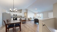 This two-story home offers a thoughtfully designed layout spread across two floors, with the main upper level comprising the majority of the living space. The main level showcases an open-concept living area where the kitchen, dining room, and living room flow seamlessly together beneath vaulted ceilings. The kitchen is outfitted with white shaker-style cabinetry, dark countertops, stainless steel appliances including a range and over-the-range microwave, and durable wood-look flooring that extends throughout the main living areas. A pendant chandelier illuminates the dining area, while the living room benefits from abundant natural light through a sliding glass door that opens to an outdoor balcony with neighborhood views.

The main level also includes two dedicated office spaces, providing flexible areas for work or study. The lower level features a more compact footprint with additional rooms and one of the three bathrooms. The primary bedroom is carpeted and includes a closet, while the bathrooms feature white vanities with dark hardware and wood-look tile flooring with a tub-shower combination. Clean neutral tones, consistent flooring, and modern black hardware create a cohesive aesthetic throughout.