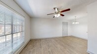 Located at 6550 Lexington Dr in Beaumont, TX, this single-story unit offers a practical and comfortable layout across two bedrooms and one bathroom. The open living room is a welcoming space highlighted by wood-style plank flooring, neutral white walls, a textured ceiling, and a ceiling fan with integrated lighting. Natural light filters in through blinds-covered windows, and an elegant pendant chandelier accents the dining area nearby.

The galley-style kitchen is well-appointed with dark cabinetry, granite countertops, a stainless steel sink, and black appliances including a refrigerator, electric range, and dishwasher. The layout maximizes counter and storage space efficiently.

Both bedrooms feature plush carpeting and ceiling fans. The spacious primary bedroom includes a walk-in closet and generous room for furnishings, while the second bedroom offers a window for natural light and an electrical panel conveniently located within the room.

The bathroom is finished with granite countertops, an undermount sink, and dark wood cabinetry with mirror accents. A dedicated utility closet houses the water heater. Throughout, the unit maintains a clean, consistent aesthetic with neutral tones and functional finishes that balance comfort and practicality.