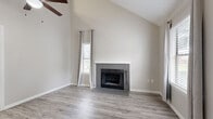 This two-story, three-bedroom, two-bathroom residence at 3304 Golden Rd in Tyler, Texas offers a functional and well-appointed layout across two floors. The main level serves as the heart of the home, featuring a bright living room with soaring vaulted ceilings, a tile-surround wood-burning fireplace, and multiple windows that flood the space with natural light. Wood-look luxury vinyl plank flooring runs throughout the main level, complementing the neutral gray-toned walls.

The kitchen is thoughtfully designed with white shaker-style cabinetry, light quartz countertops, a classic subway tile backsplash, and a full suite of stainless steel appliances including a range, microwave, dishwasher, and refrigerator. A peninsula provides additional prep and serving space.

The primary bedroom is generously sized and connects to a full bathroom. Two additional bedrooms offer comfortable accommodations, with one located on the upper level featuring carpet flooring, a ceiling fan, angled architectural details, and a window with outdoor views. Both bathrooms include tub/shower combinations with clean, white tile surrounds and wood-look flooring. The overall aesthetic is modern and move-in ready, with a cohesive neutral palette throughout.